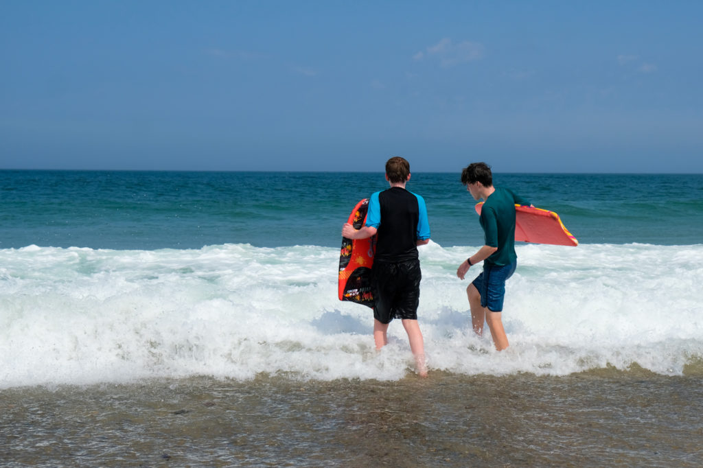 two boys at beach with boogie boards