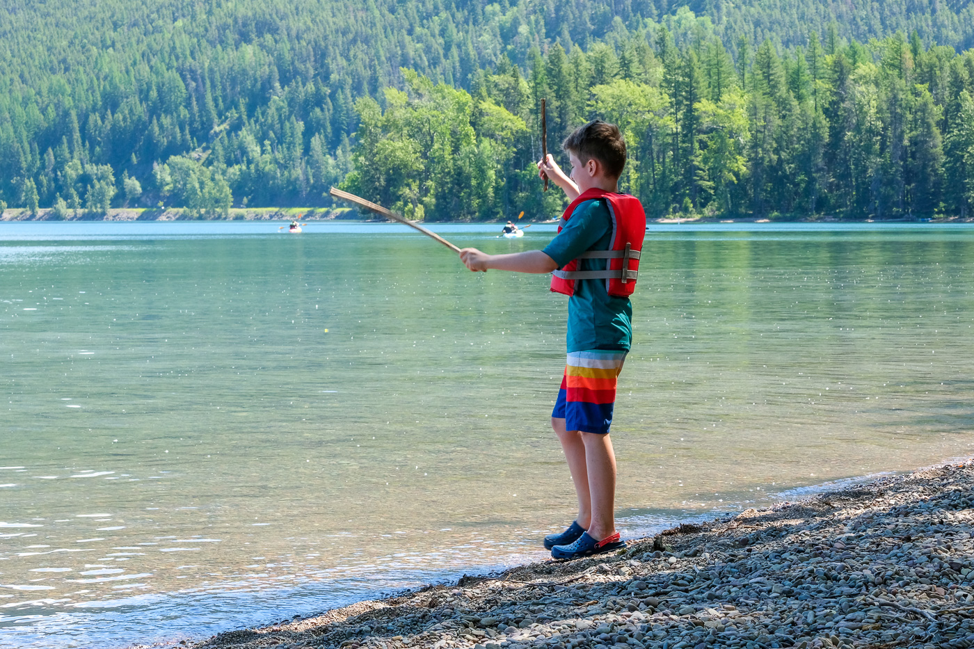 Side view of teenage boy fishing with rod in lake while standing