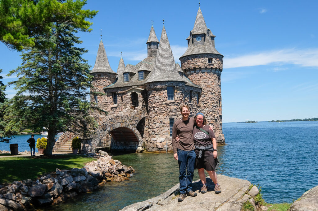 two people in front of small stone castle-like building